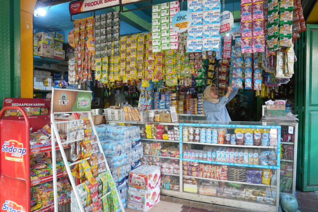 Shop with dairy products at a local 'pasar', a covered market. These traditional sales channels account for half of sales. Other channels are mini markets and supermarkets. Above the counter hang the popular 38 gram bags, which are sold in strings of 6 pieces.